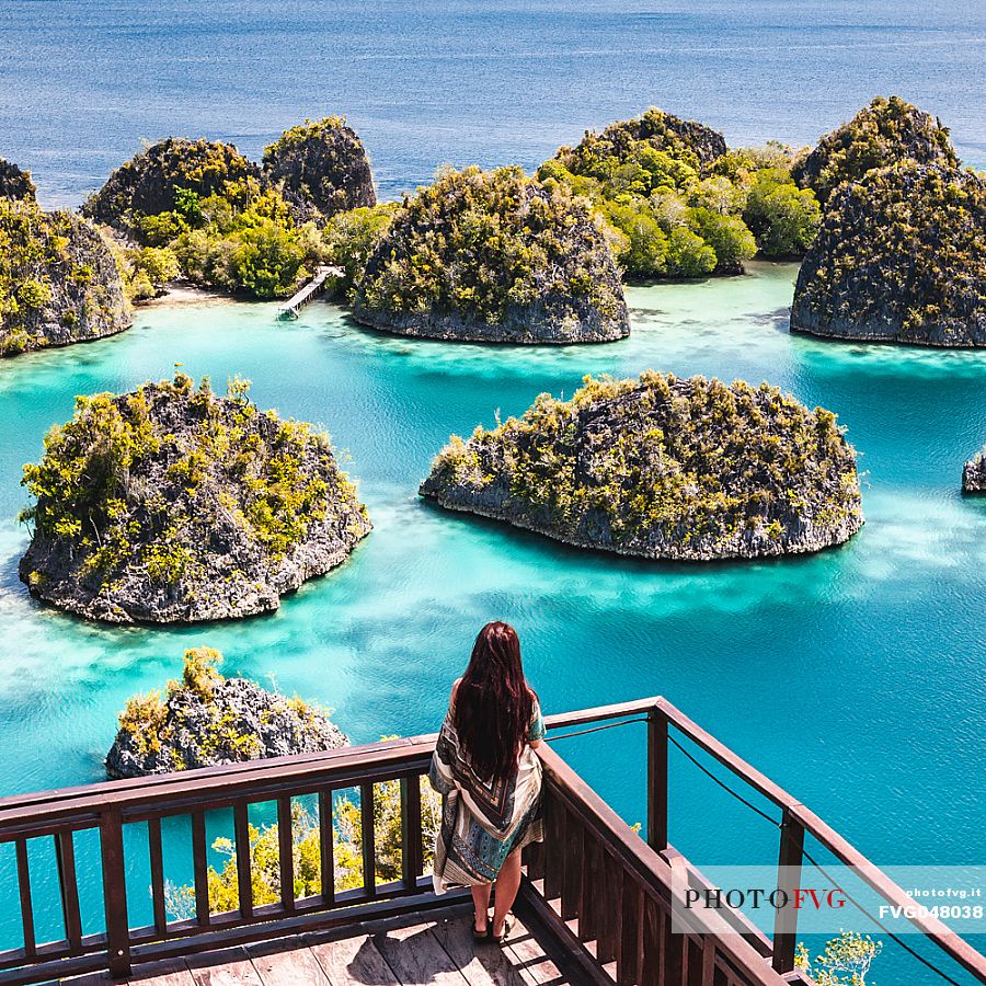 Woman enjoying the landscape from the scenic viewpoint in Piaynemo, one of the Raja Ampat archipelago most popular tourist spots, West Papua, New Guinea, Indonesia.
