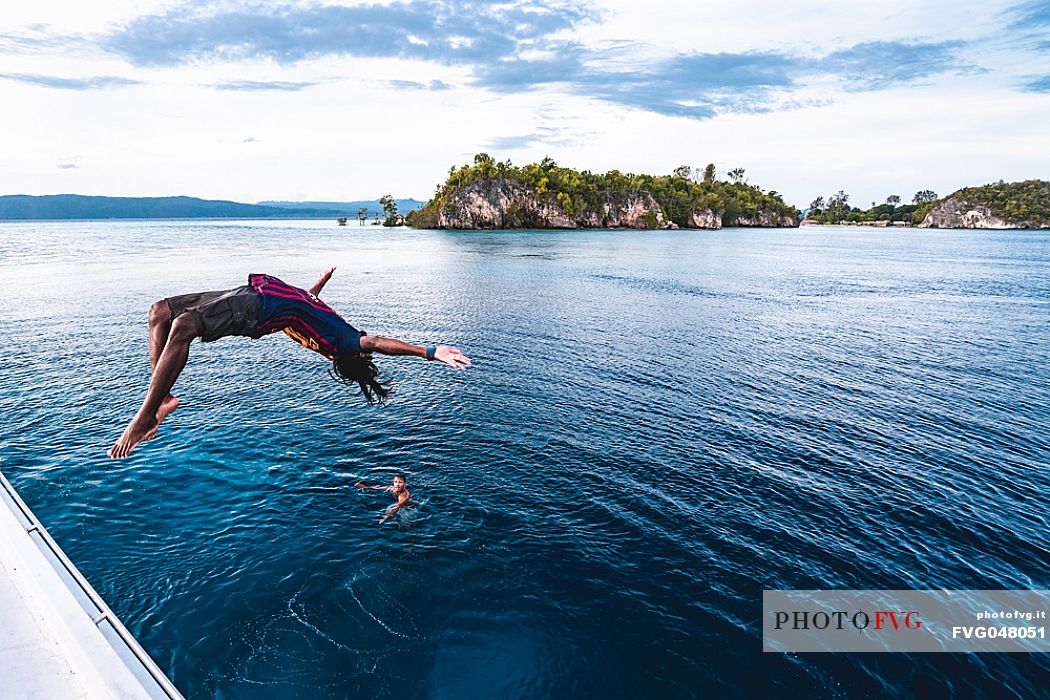 Local man dives in the wonderful sea of the Kri island, one of the Raja Ampat archipelago most popular tourist spots, West Papua, Indonesia