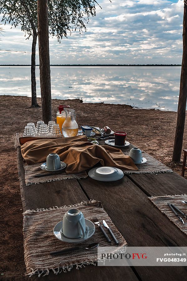 Breakfast mugs on the wooden table in front of Flamenco lagoon in the Paraguayan Chaco near the Reserva Natural - Campo María, Paraguay, America