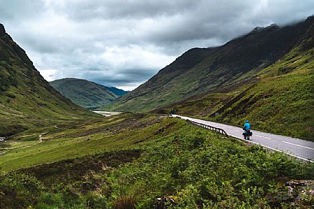 A cyclist that travel around Scotland passing in the Three Sisters of Glencoe area, Scotland, United Kingdom