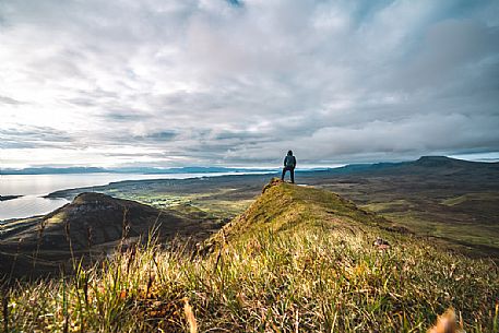 A hiker enjoying the view at lunar landscape of Quiraing on the Trotternish peninsula, Isle of Skye, Scotland, United Kingdom, Europe