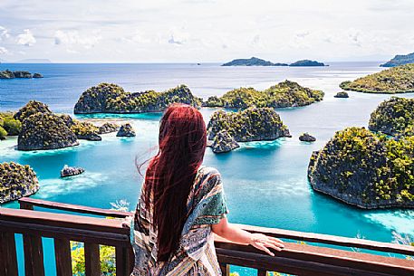 Woman enjoying the landscape from the scenic viewpoint in Piaynemo, one of the Raja Ampat archipelago most popular tourist spots, West Papua, New Guinea, Indonesia.