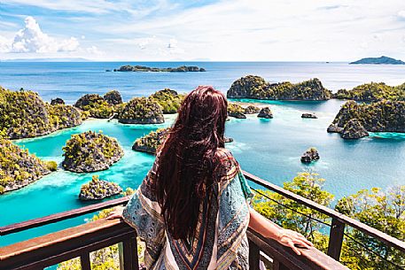 Woman enjoying the landscape from the scenic viewpoint in Piaynemo, one of the Raja Ampat archipelago most popular tourist spots, West Papua, New Guinea, Indonesia.