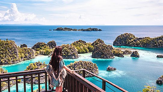 Woman enjoying the landscape from the scenic viewpoint in Piaynemo, one of the Raja Ampat archipelago most popular tourist spots, West Papua, New Guinea, Indonesia.