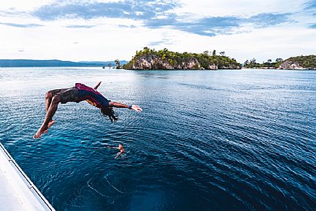 Local man dives in the wonderful sea of the Kri island, one of the Raja Ampat archipelago most popular tourist spots, West Papua, Indonesia
