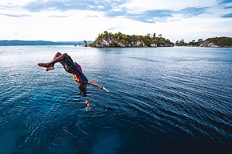 Local man dives in the wonderful sea of the Kri island, one of the Raja Ampat archipelago most popular tourist spots, West Papua, Indonesia