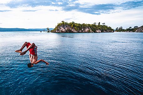 Local man dives in the wonderful sea of the Kri island, one of the Raja Ampat archipelago most popular tourist spots, West Papua, Indonesia