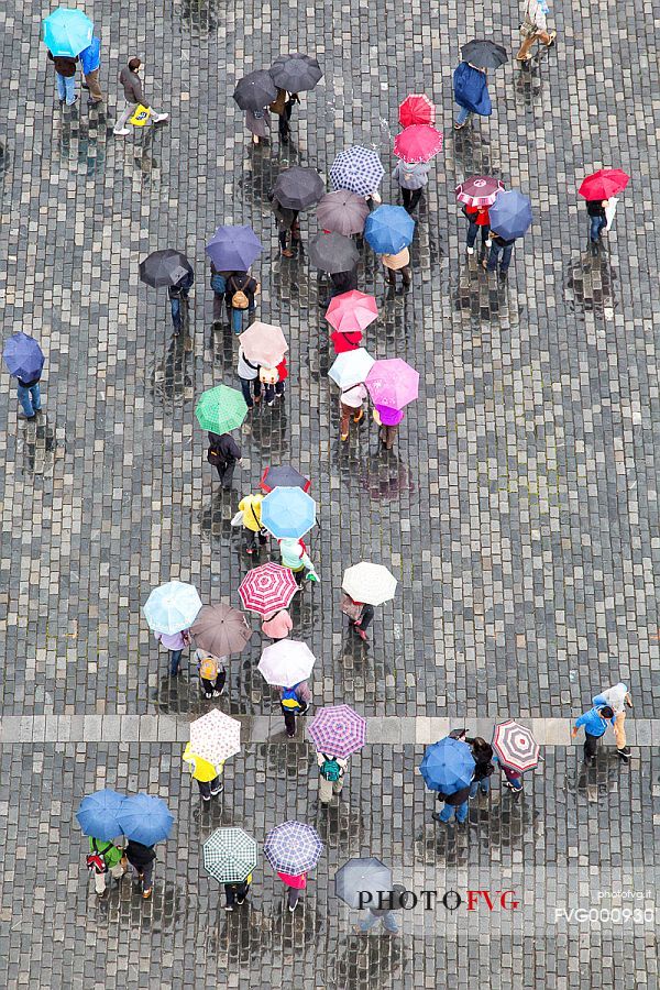 Tourists walking in Old Town Square, Staromestsk Nmest, with coloured umbrellas
