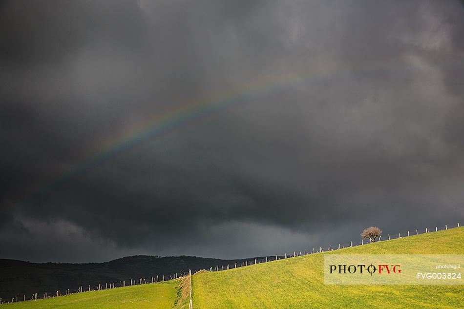 Light rainbow over rain clouds