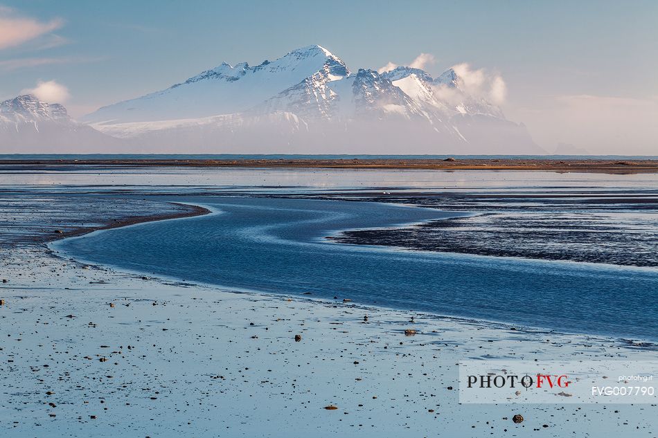 Saltwater lagoon along the coast of Iceland and mountains in the background.