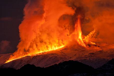 Etna 2nd paroxysm activity of 2012, a lava flow meets snow forming huge clouds of vapor illuminated in red.