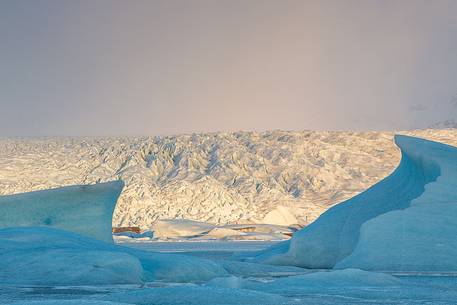 Iceberg on lagoon and sunlight on glacier in backgroud