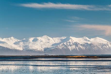 Saltwater lagoon along the coast of Iceland and mountains in the background.
