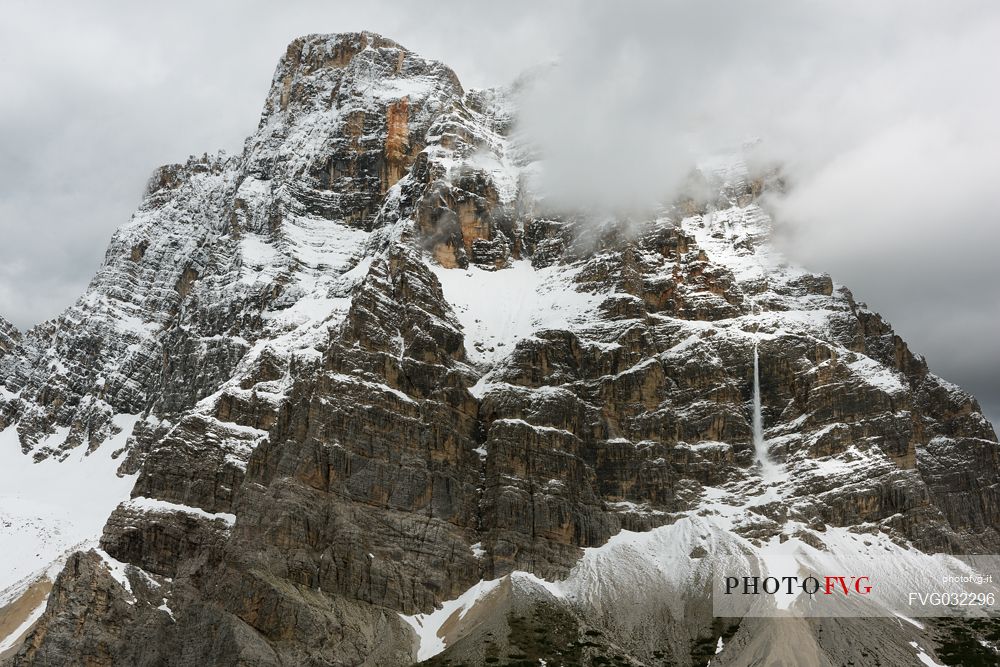 Mount Pelmo, after an abundant spring snowfall. Surrounded by threatening clouds, it releases the load of its snow into frequent and noisy avalanches, Zoldana valley, dolomites, Italy