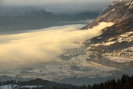 The fog descends on the villages of the Alpgao, Pieve d'Alpago village from above, Cansiglio forest, Veneto, Italy, Europe