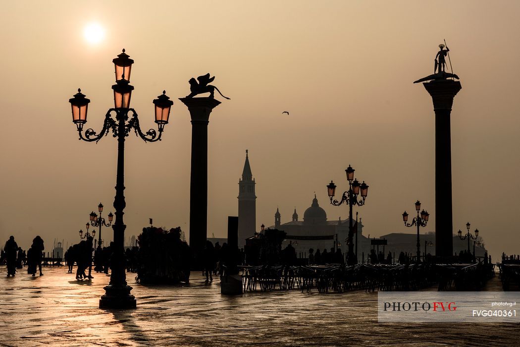 Tourists in Saint mark square with San Marco and San Todaro columns in the foggy day, view towards San Giorgio Maggiore island, Venice, Veneto, Italy, Europe