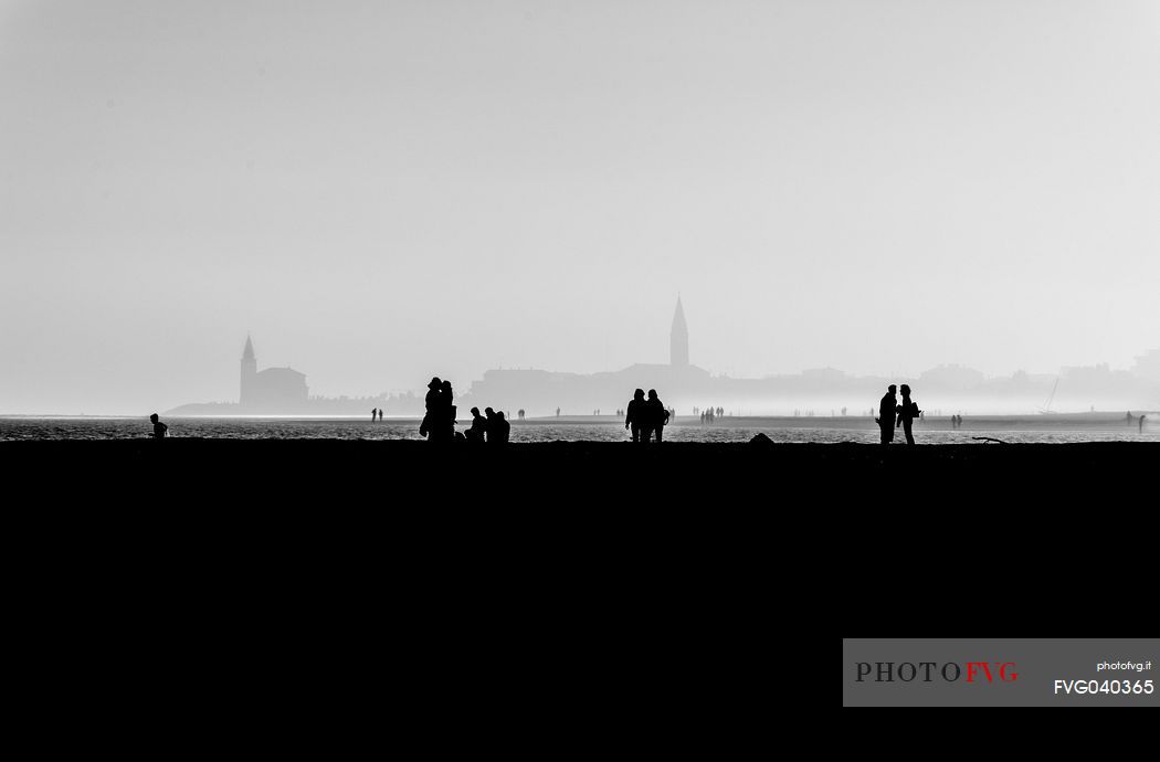 Whispers in the promenade of Caorle. Sillhouette at sunset on a foggy october evening, Caorle, Veneto, Italy, Europe