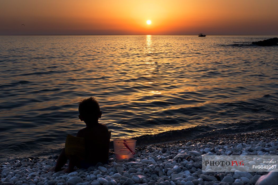 Child in backlight at sunset on the Macari beach, San Vito Lo Capo, Trapani, Sicily, Italy, Europe