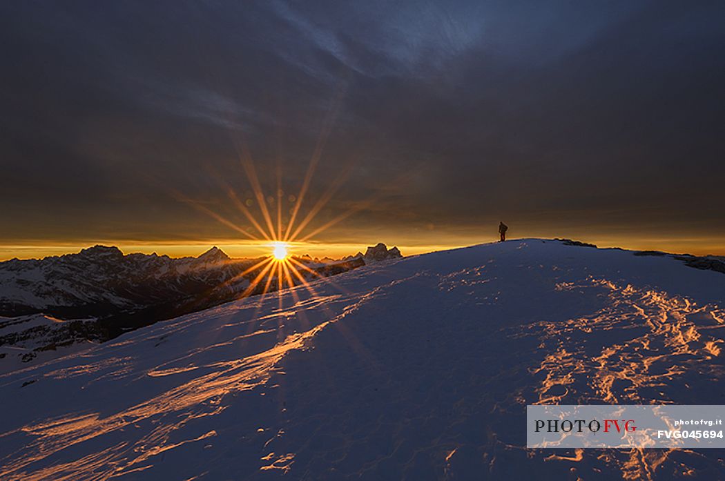 Hiker on the top of Lagazuoi mountain at dawn, in the background Sorapiss, Antelao and  Pelmo, dolomites, Cortina d'Ampezzo, Veneto, Italy, Europe

