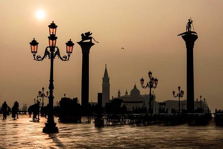 Tourists in Saint mark square with San Marco and San Todaro columns in the foggy day, view towards San Giorgio Maggiore island, Venice, Veneto, Italy, Europe