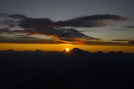 The sun rises behind Mount Pelmo taken from the top of Mulaz in a Pale di San Martino mountain group, dolomites, Trentino Alto Adige, Italy
