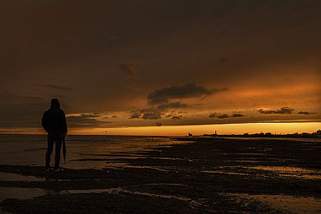 Man admires the sunset in Caorle after a thunderstorm, Adriatic sea, Veneto, Italy, Europe