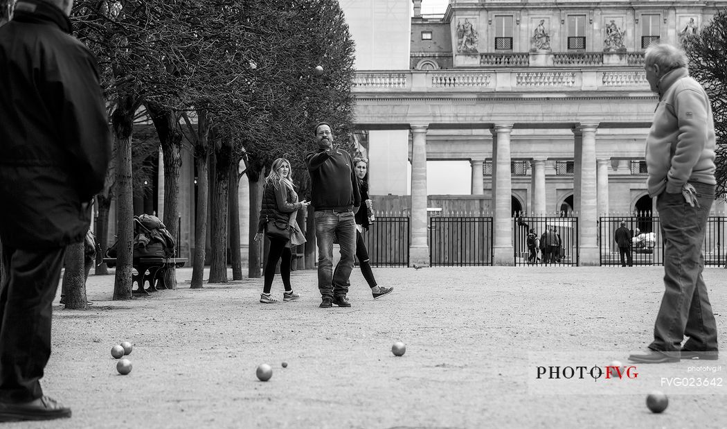 People playing the french game petanque (Bowls games) into the Palais Royale gardens, Paris, France