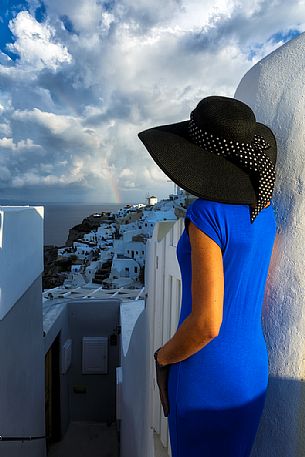 Panoramic view of Santorini island from old church ruins in Oia with a model in blue dress color.Rainbow time,Greece