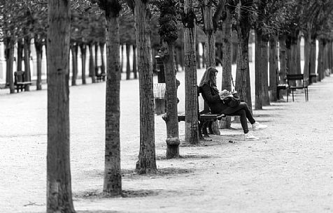 One girl seated is reading a book.Palais Royale. Paris, France