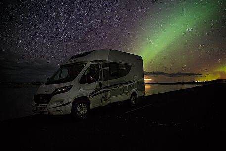 Camper and northern lights at Reynisfjara lagoon, Iceland