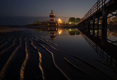 Pier and the old lighthouse by night in Lignano Sabbiadoro, Friuli Venezia Giulia, Italy