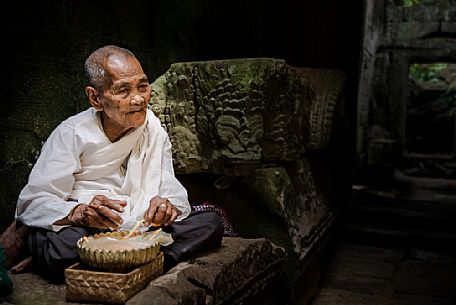 Old woman making bracelets in a Preah Kan temple