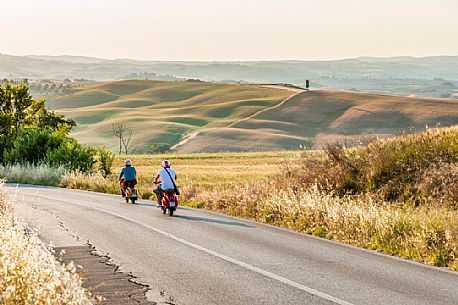 On the road with Vespa in the Crete Senesi landscape, Orcia valley, Tuscany, Italy