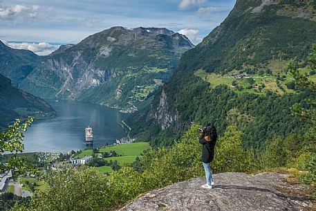 Tourist at the Flydalsjuvet rock looking the Geiranger fjord, Norway