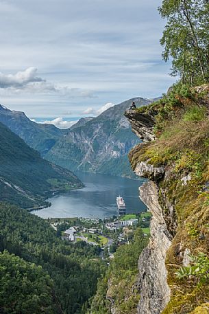 Girl relaxing on the Flydalsjuvet rock, over the Geiranger fjord, Norway