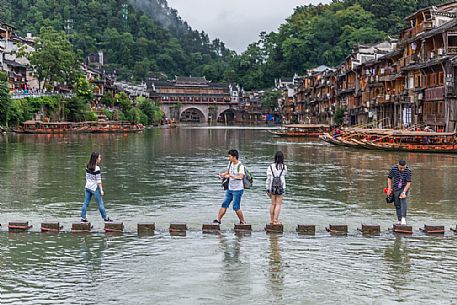 Tourist visiting the ancient village of Fenghuang along the Tuo Jiang River, in the background the Phoenix Hong bridge, Hunan, Cina
