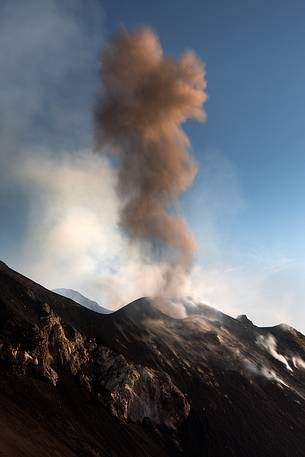 An explosion produces a coloumn of smoke. Lava and lapilli flow along the Sciara del Fuoco