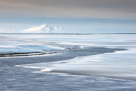 An area of  frozen sea nearby the Jokulsarlon lagoon. A snow covered mountain in the background